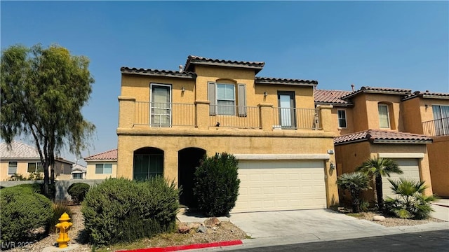 mediterranean / spanish house featuring a garage, concrete driveway, a balcony, and stucco siding