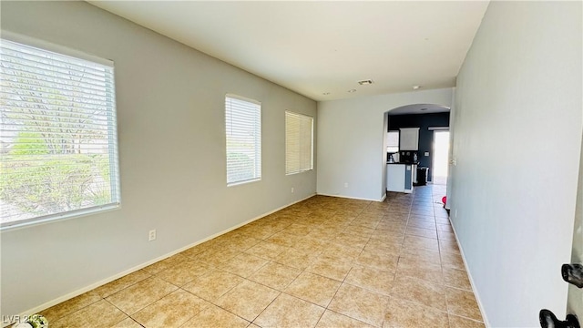 spare room with a healthy amount of sunlight, visible vents, arched walkways, and light tile patterned flooring