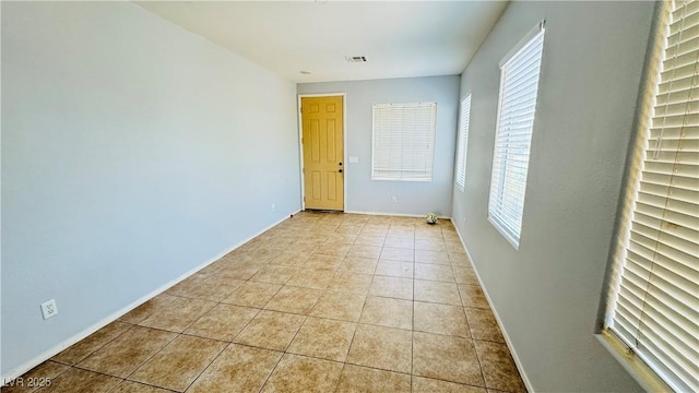 empty room with visible vents, baseboards, and light tile patterned floors