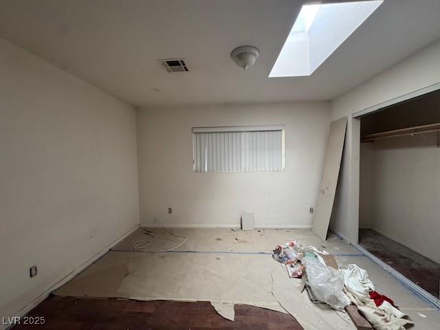 unfurnished bedroom with a closet, a skylight, and visible vents