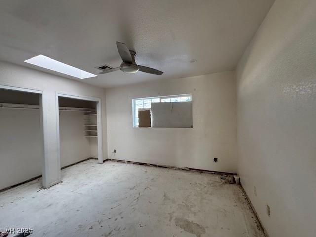 unfurnished bedroom featuring ceiling fan, unfinished concrete flooring, visible vents, and multiple closets