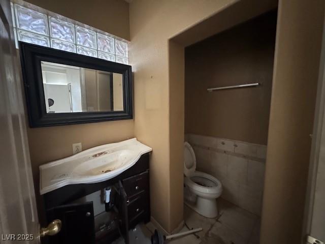 bathroom featuring tile walls, vanity, and toilet