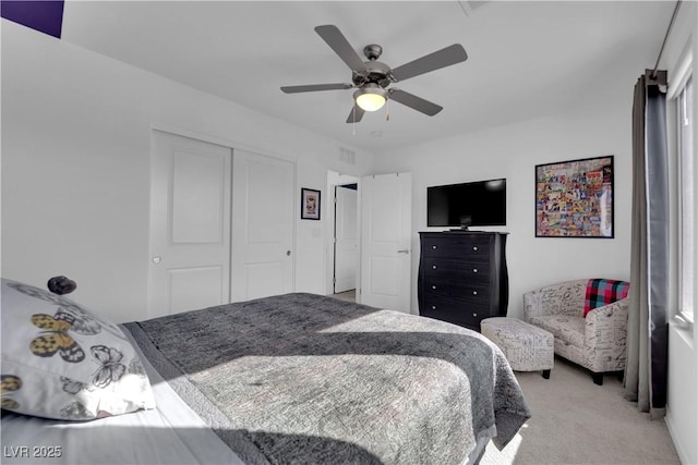 bedroom with a ceiling fan, visible vents, a closet, and light colored carpet