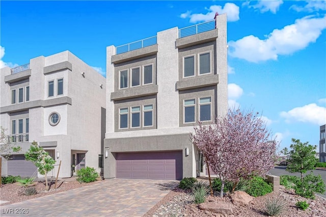 view of front of home featuring decorative driveway, an attached garage, and stucco siding