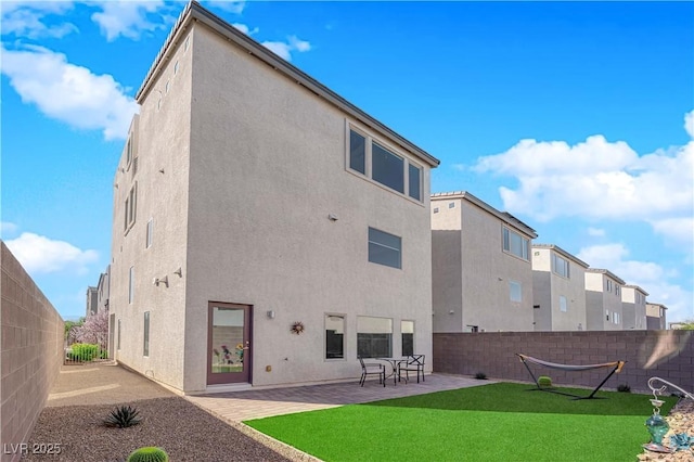 rear view of house featuring a yard, a fenced backyard, a patio, and stucco siding