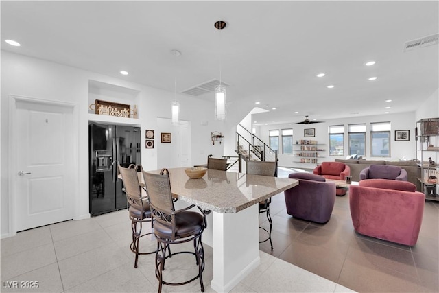 kitchen featuring a breakfast bar, visible vents, recessed lighting, and black fridge