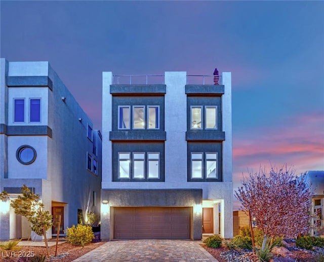 modern home featuring an attached garage, decorative driveway, and stucco siding