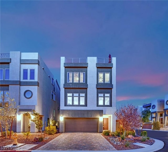 view of front of house featuring a garage, decorative driveway, and stucco siding