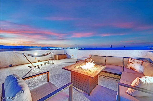 patio terrace at dusk with an outdoor living space with a fire pit