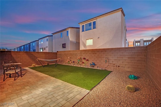 yard at dusk featuring a patio area and a fenced backyard