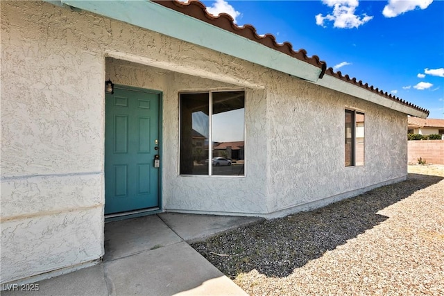 entrance to property featuring a tiled roof and stucco siding