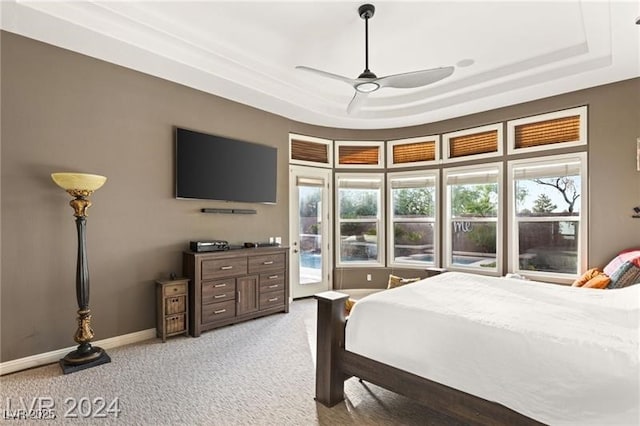 bedroom with light carpet, a ceiling fan, baseboards, access to outside, and a raised ceiling