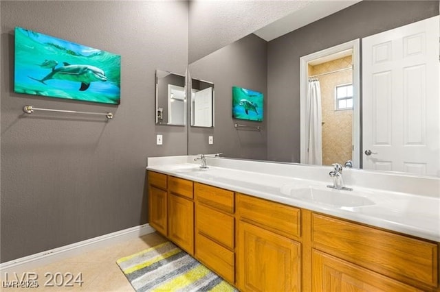 full bath with baseboards, double vanity, a sink, and tile patterned floors