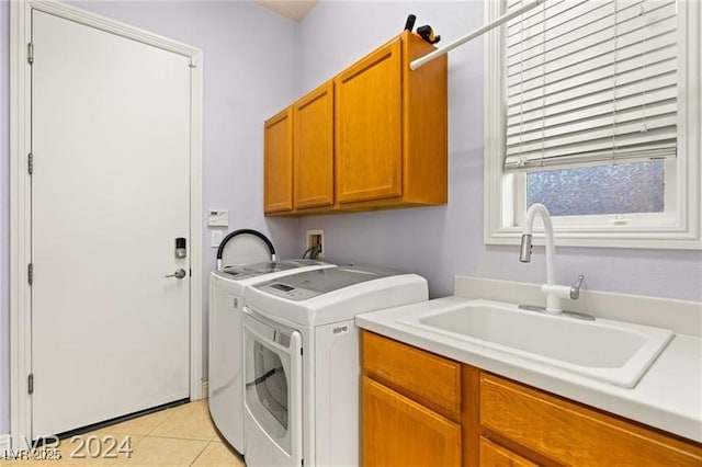 clothes washing area featuring cabinet space, washing machine and dryer, a sink, and light tile patterned flooring