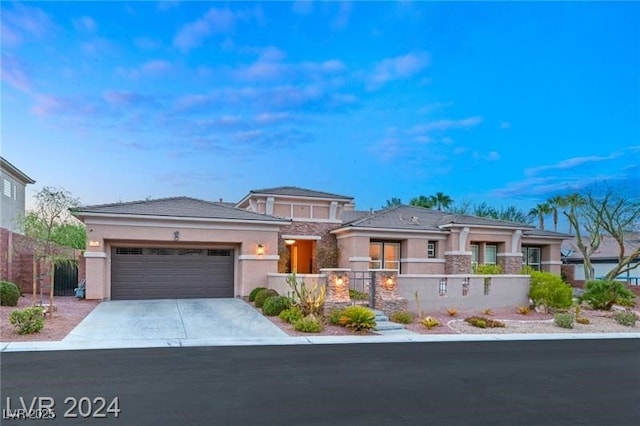 prairie-style home with a garage, driveway, a fenced front yard, and stucco siding