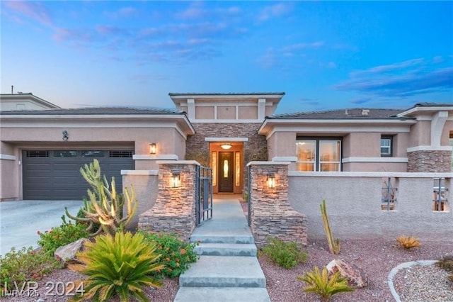 prairie-style home featuring stone siding, a fenced front yard, and stucco siding