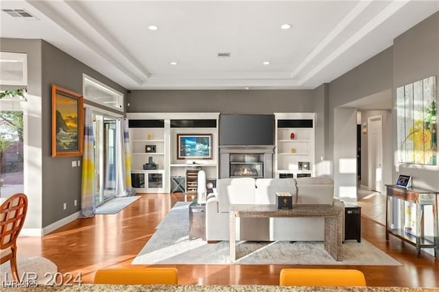 living room with baseboards, visible vents, wood finished floors, and a glass covered fireplace