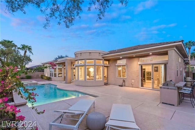 rear view of property featuring a patio area, outdoor dry bar, an outdoor pool, and stucco siding