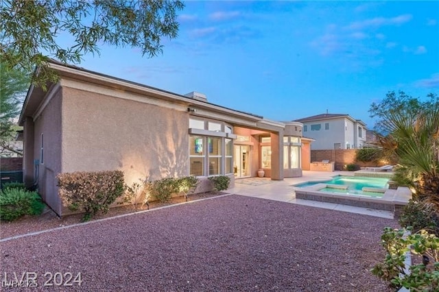 rear view of house with a fenced in pool, a patio, fence, and stucco siding