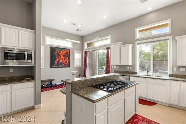 kitchen with stainless steel microwave, a sink, gas stovetop, and light tile patterned floors