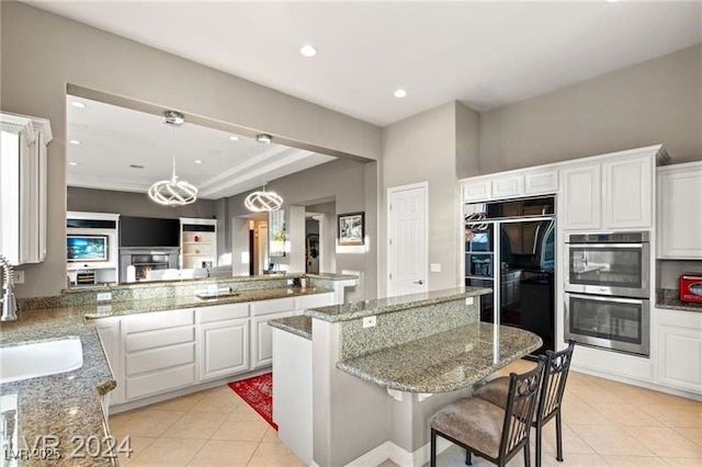 kitchen with light tile patterned floors, light stone counters, stainless steel double oven, a sink, and white cabinetry