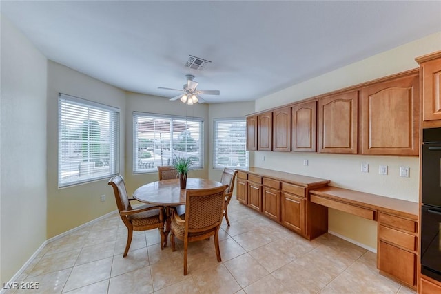 dining room with baseboards, plenty of natural light, a ceiling fan, and built in desk