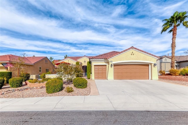 mediterranean / spanish-style house featuring a garage, concrete driveway, a tiled roof, cooling unit, and stucco siding