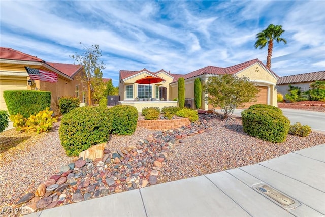 view of front of home with a tile roof, driveway, an attached garage, and stucco siding