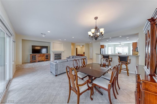 dining space with light tile patterned floors, a glass covered fireplace, visible vents, and recessed lighting