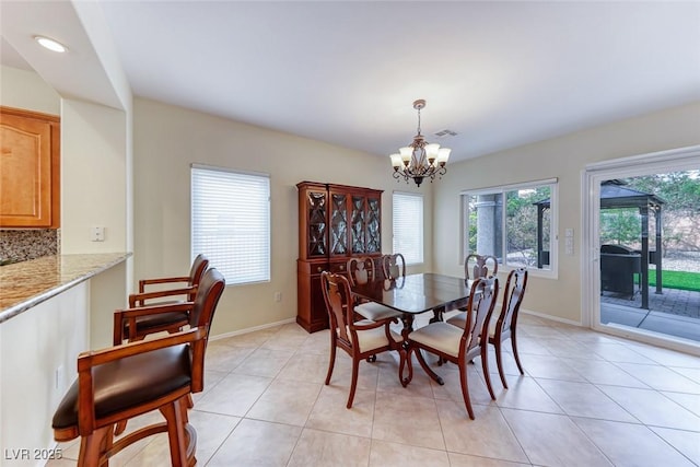 dining space with a chandelier, light tile patterned floors, and baseboards