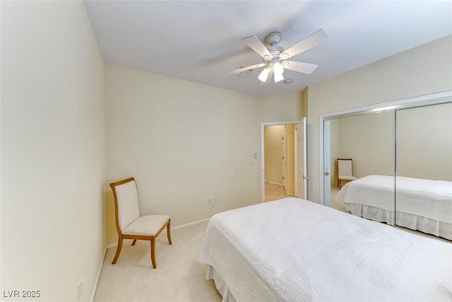 bedroom featuring a ceiling fan, a closet, light colored carpet, and baseboards