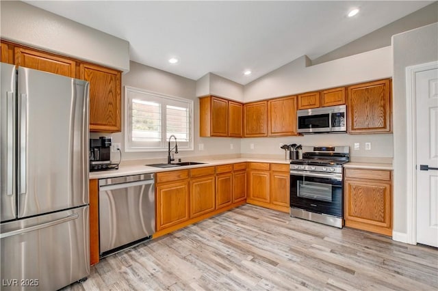 kitchen with stainless steel appliances, lofted ceiling, light countertops, and a sink