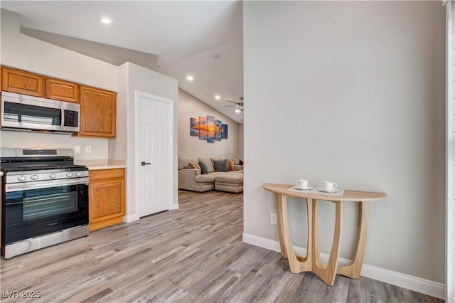 kitchen featuring appliances with stainless steel finishes, lofted ceiling, light wood-type flooring, and light countertops