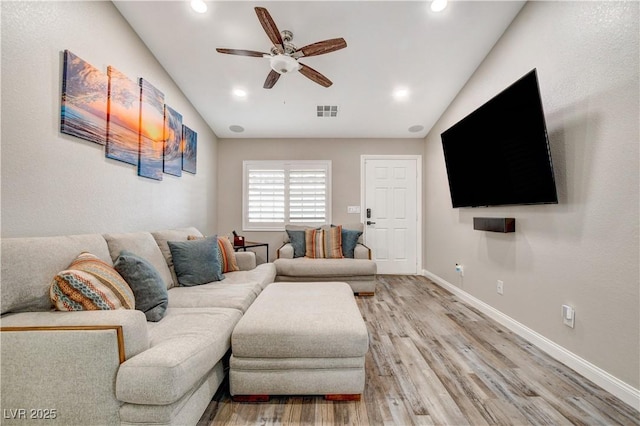 living area featuring light wood finished floors, visible vents, a ceiling fan, vaulted ceiling, and baseboards