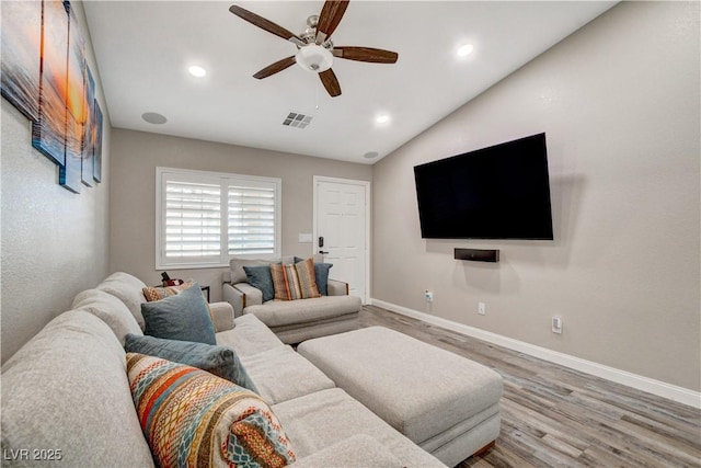 living area featuring vaulted ceiling, wood finished floors, visible vents, and baseboards