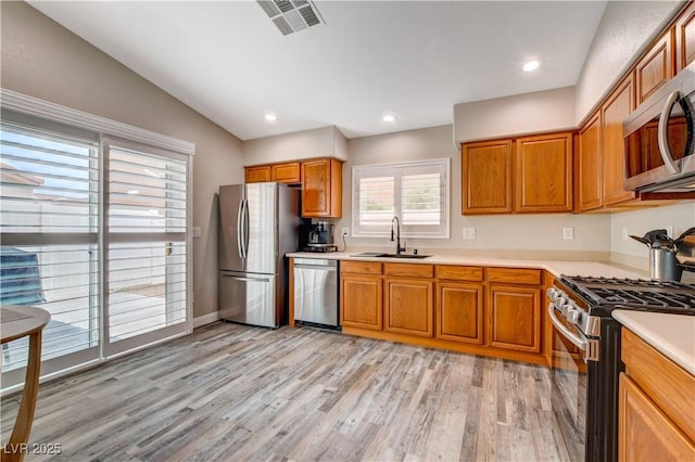 kitchen featuring stainless steel appliances, light countertops, visible vents, light wood-style floors, and a sink