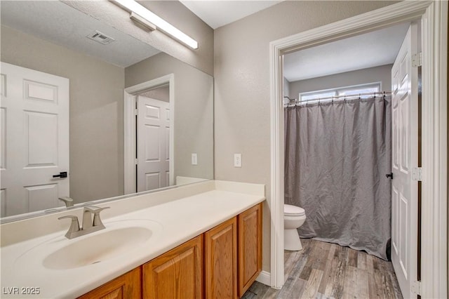 full bath featuring visible vents, a shower with shower curtain, toilet, wood finished floors, and vanity