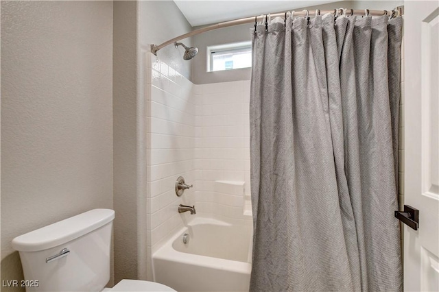 bathroom with a textured wall, shower / bath combo with shower curtain, and toilet