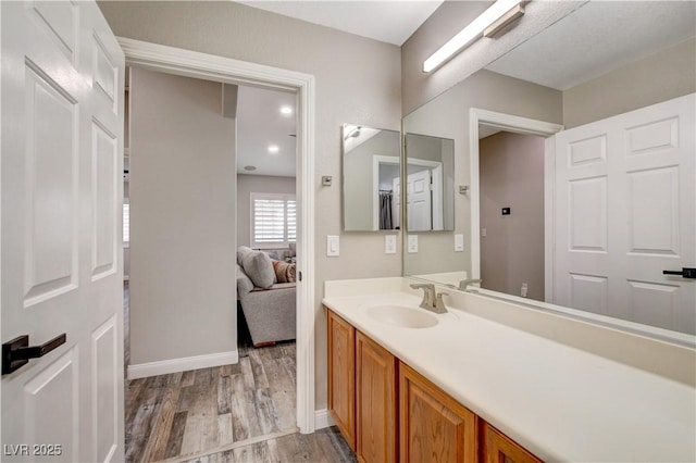 bathroom featuring vanity, baseboards, and wood finished floors