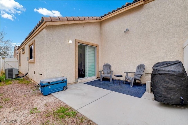 exterior space with a patio, central AC unit, fence, a tiled roof, and stucco siding