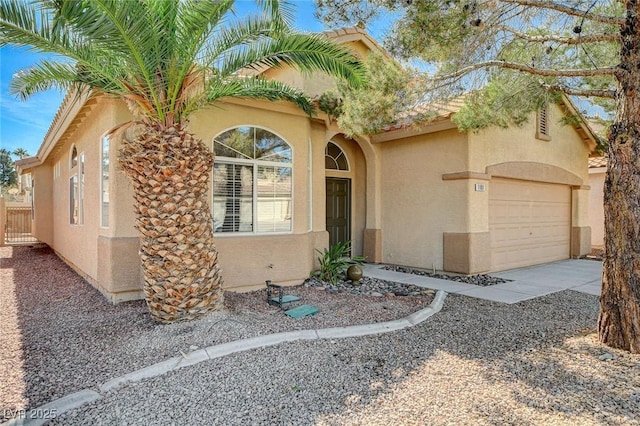 mediterranean / spanish house featuring driveway, an attached garage, and stucco siding