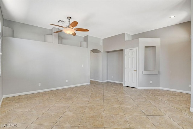 tiled empty room featuring arched walkways, visible vents, ceiling fan, and baseboards