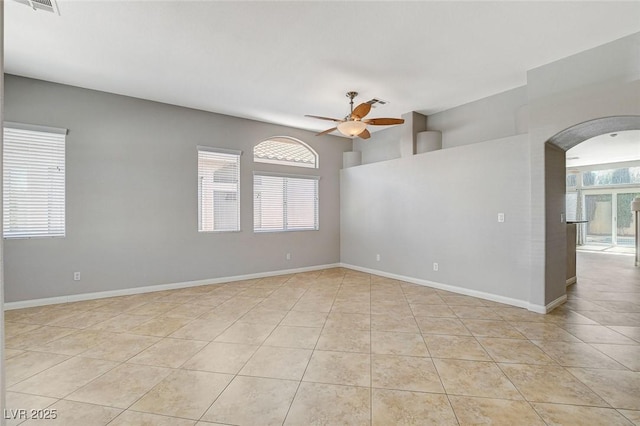 spare room with a ceiling fan, light tile patterned flooring, plenty of natural light, and baseboards