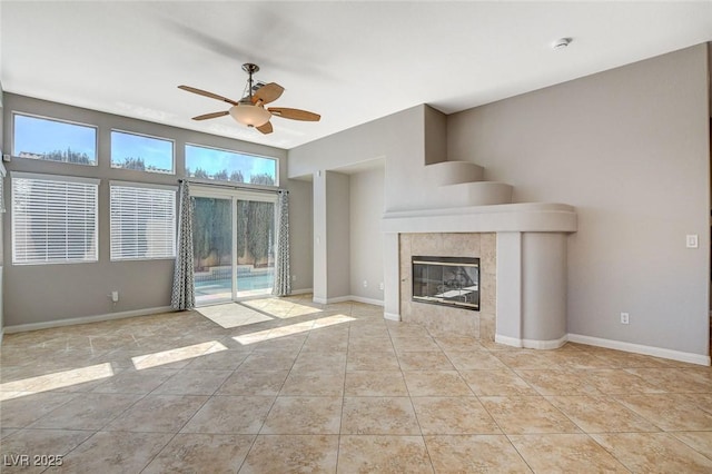 unfurnished living room with light tile patterned floors, ceiling fan, a fireplace, and baseboards