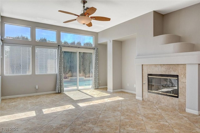 unfurnished living room featuring ceiling fan, a fireplace, tile patterned floors, and baseboards