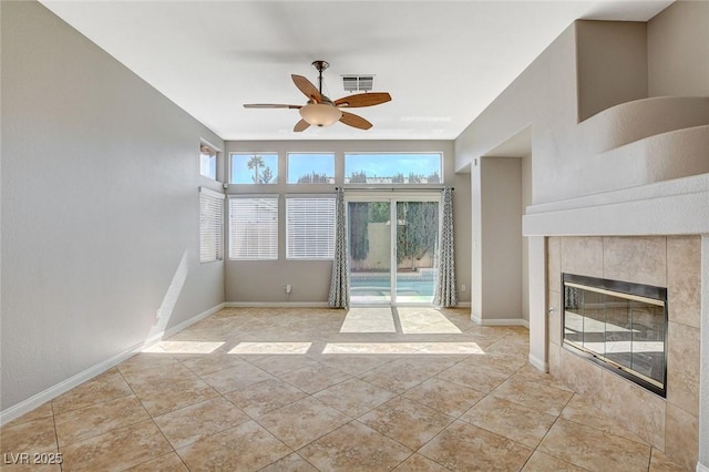 unfurnished living room with light tile patterned floors, ceiling fan, a tile fireplace, visible vents, and baseboards