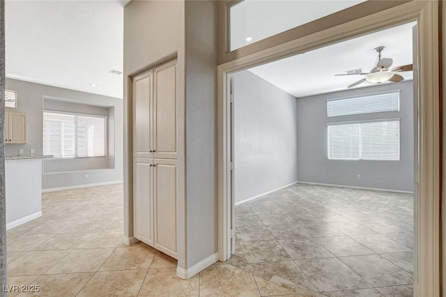 corridor with visible vents, baseboards, and light tile patterned floors