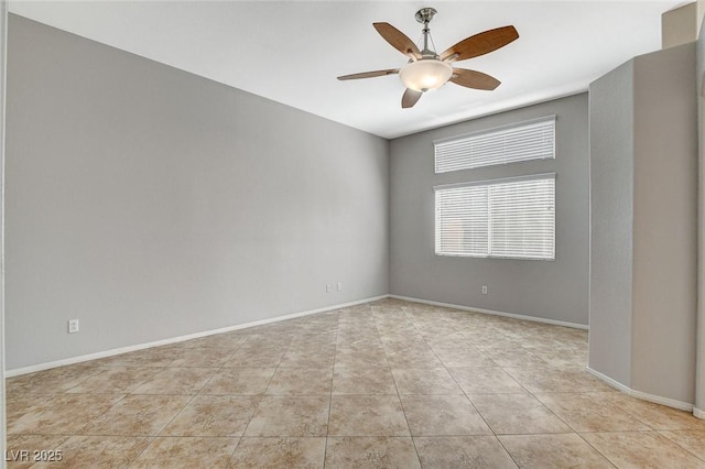 spare room featuring tile patterned floors, a ceiling fan, and baseboards