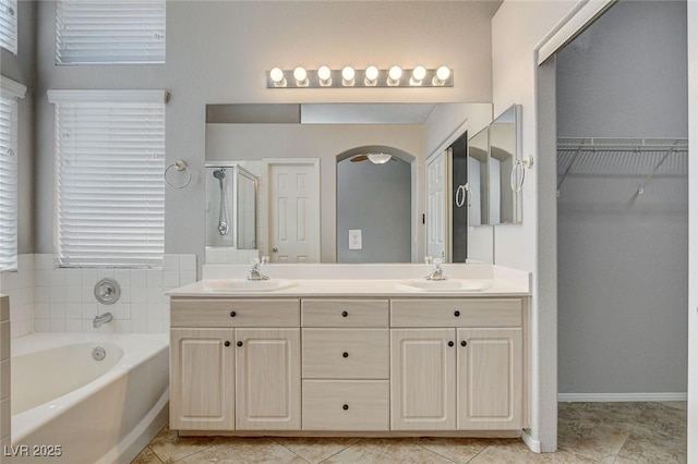 bathroom with double vanity, a garden tub, a shower stall, and a sink