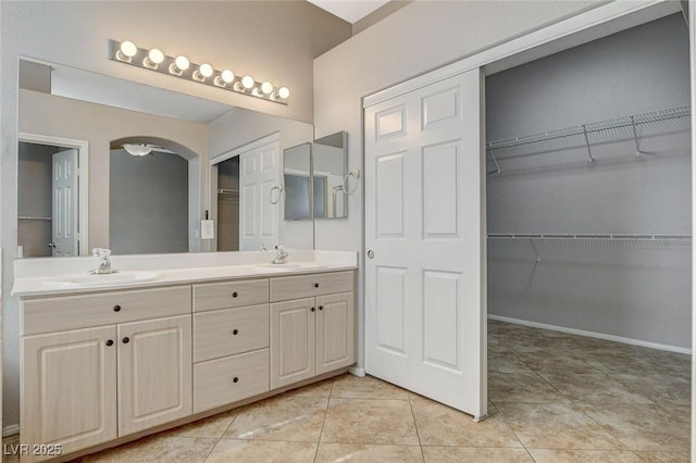 full bath featuring double vanity, tile patterned flooring, a walk in closet, and a sink